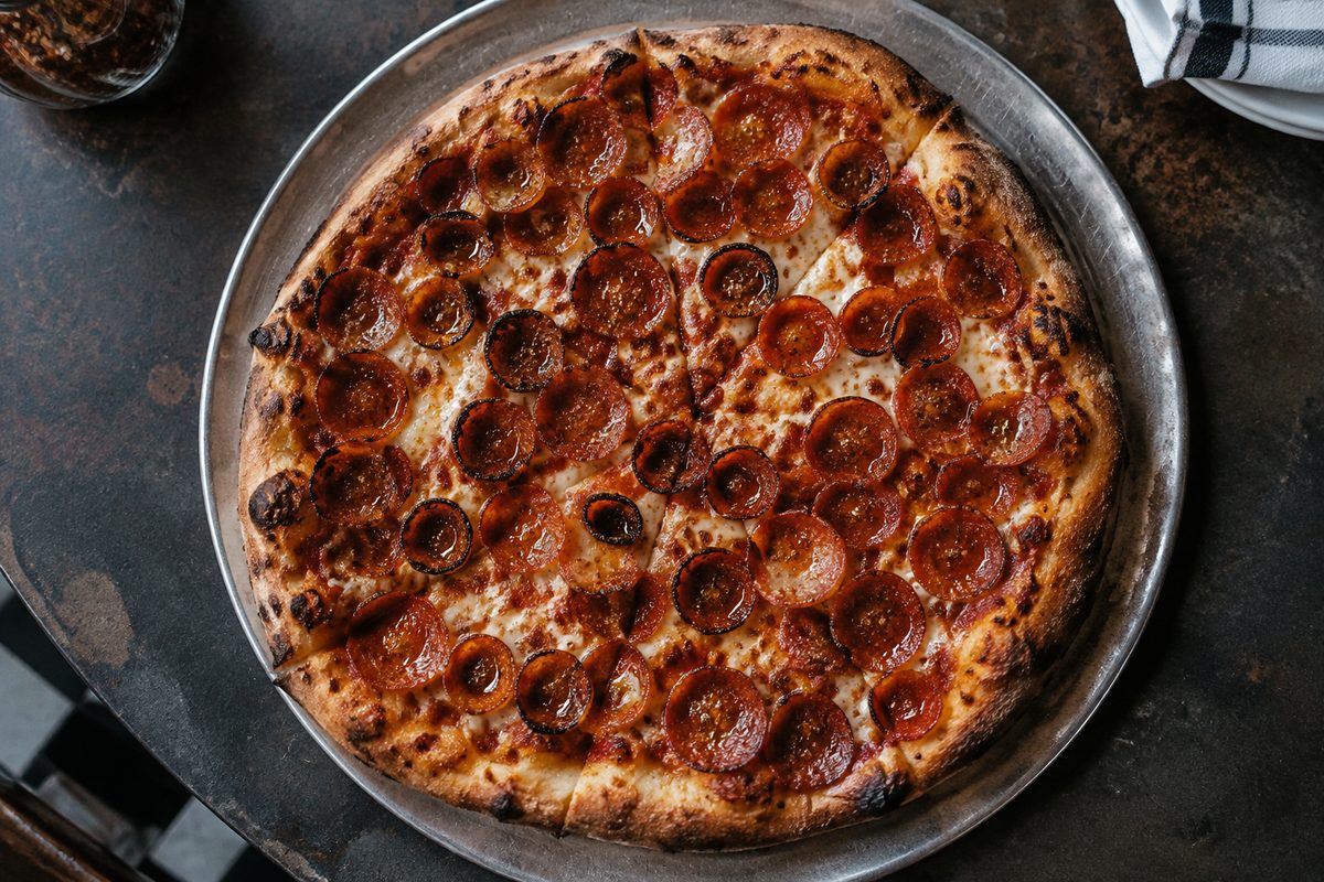 Cup-and-char pepperoni pizza baked crisp on stone deck hearth